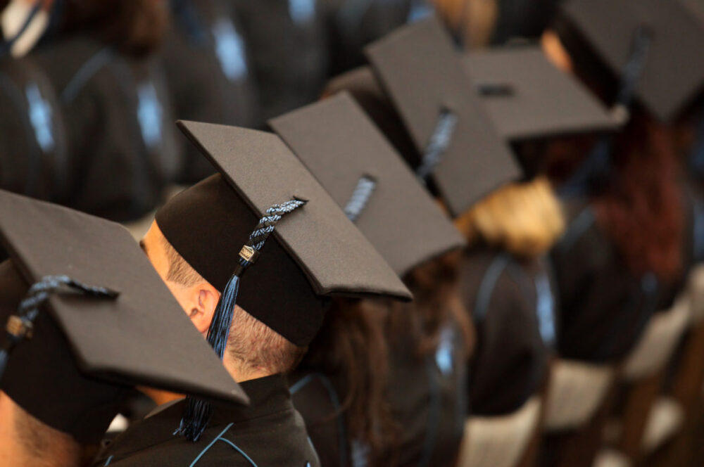 A group of students with tassels and robes seated at high school graduation