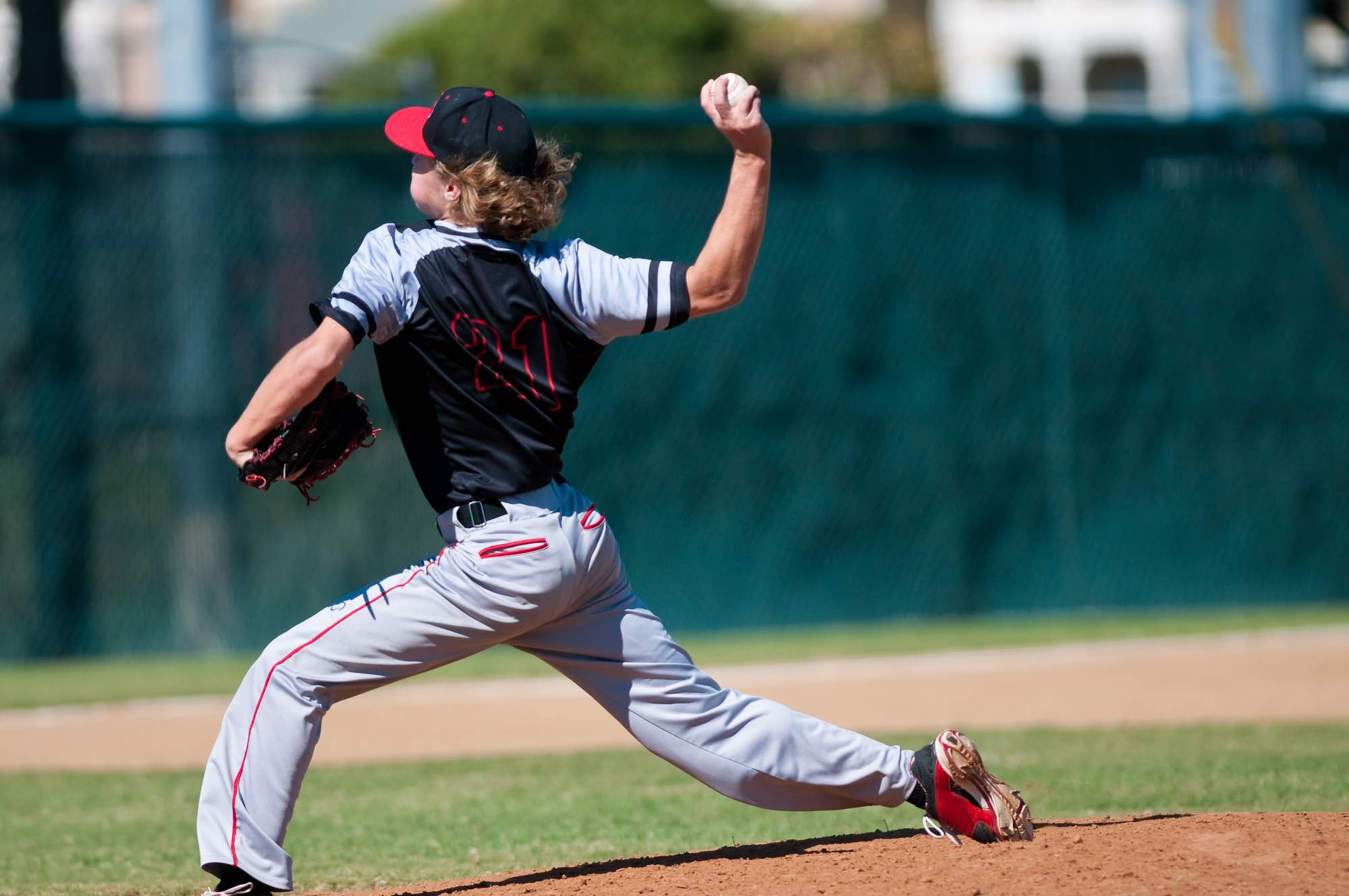 High school baseball pitcher throwing ball from mound