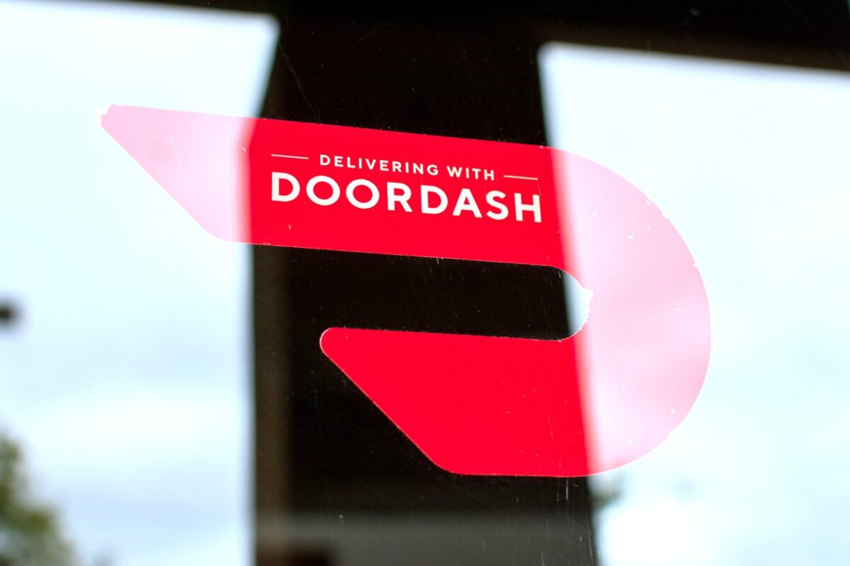 Close up. A red sticker decal on a restaurant door advertising delivery service available through DoorDash