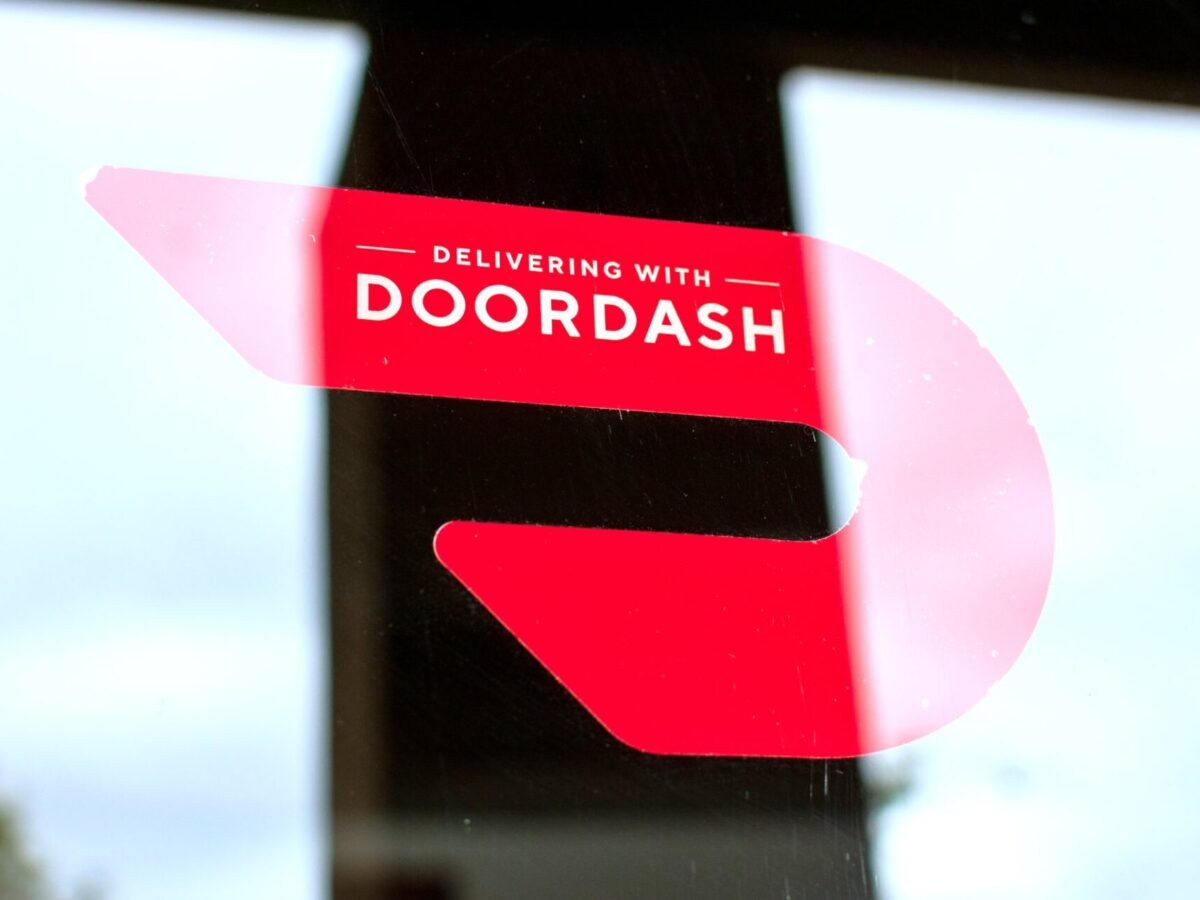 Close up. A red sticker decal on a restaurant door advertising delivery service available through DoorDash