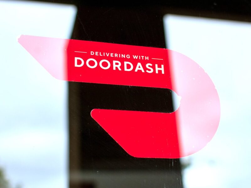 Close up. A red sticker decal on a restaurant door advertising delivery service available through DoorDash