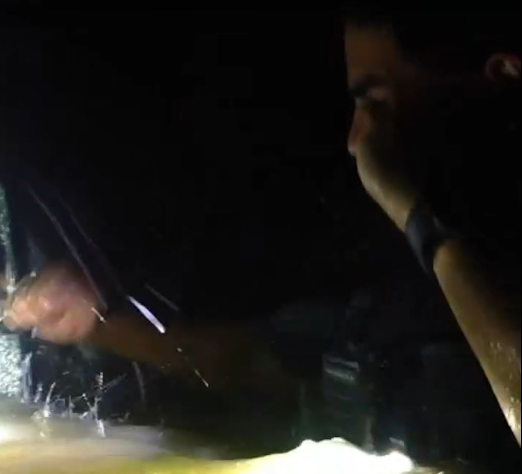 An OPD officer shattering one of the car's windows in order to search the interior for any remaining occupants. (Photo: Ocala Police Department)